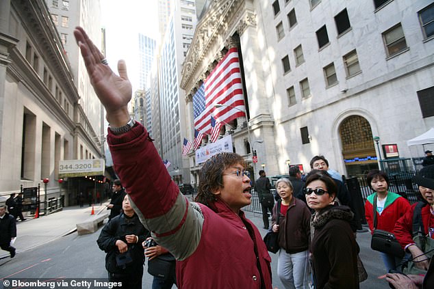 The advisory reminded visitors from China that physical fighting between couples in the US was not regarded as a trivial matter. Above, Chinese visitors take photos on Wall Street