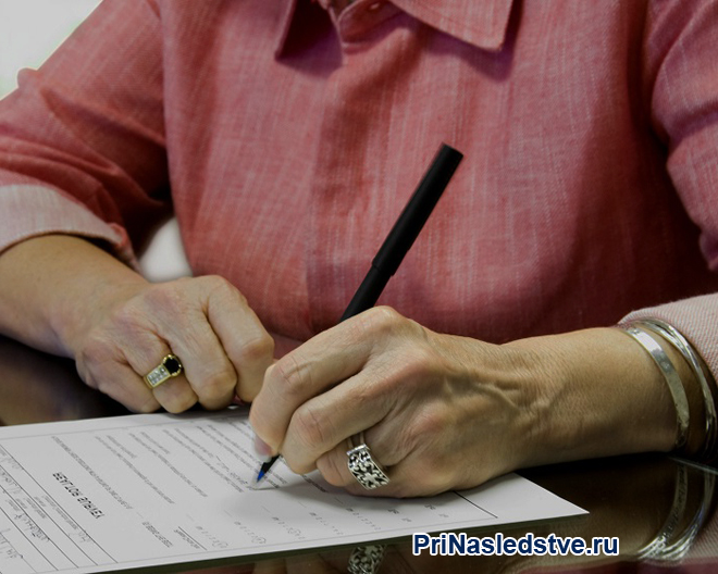 Женщина подписывает документы